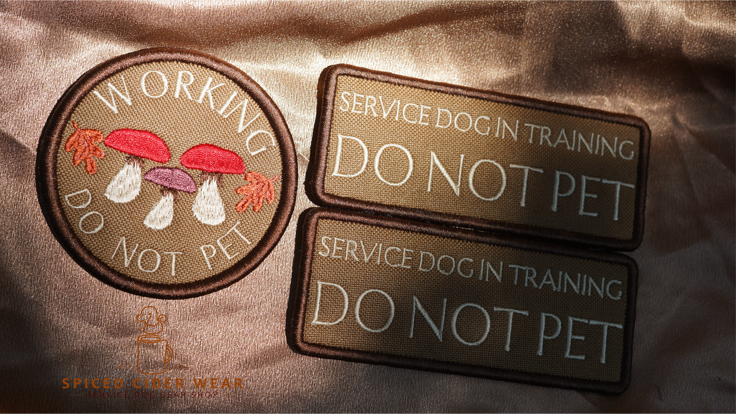 Three patches on a brown fabric background, including 'Working Do Not Pet', 'Service Dog in Training Do Not Pet', and 'Service Dog in Training'.